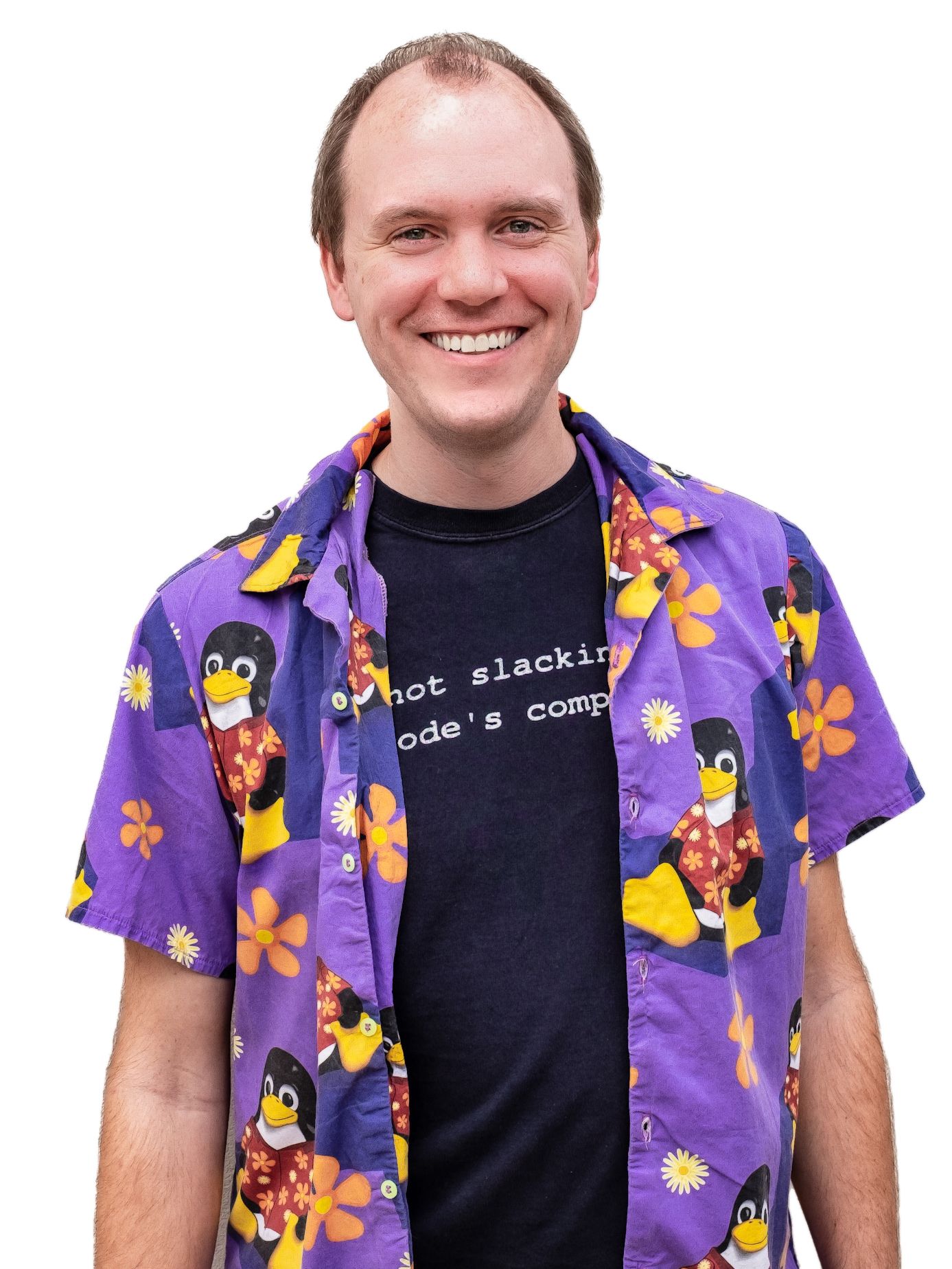 A photo of Matt DeKrey, smiling and wearing an aloha-style shirt. The print of the shirt is a pattern with Tux wearing an floral aloha-style shirt.